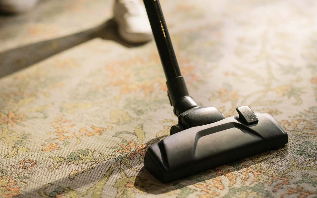 A person vacuuming a carpet with a professional vacuum cleaner
